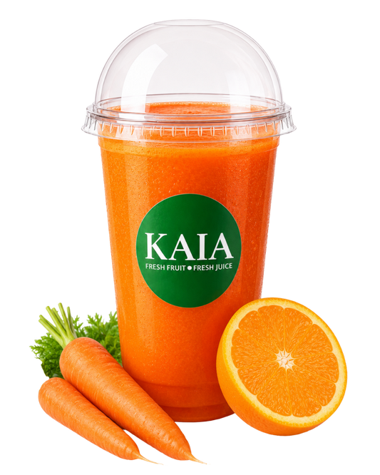 Deep Orange & Carrot juice in a clear plastic cup with a KAIA label, surrounded by carrots and an orange.