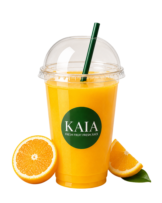 Orange juice in a KAIA cup with a straw, surrounded by orange slices.